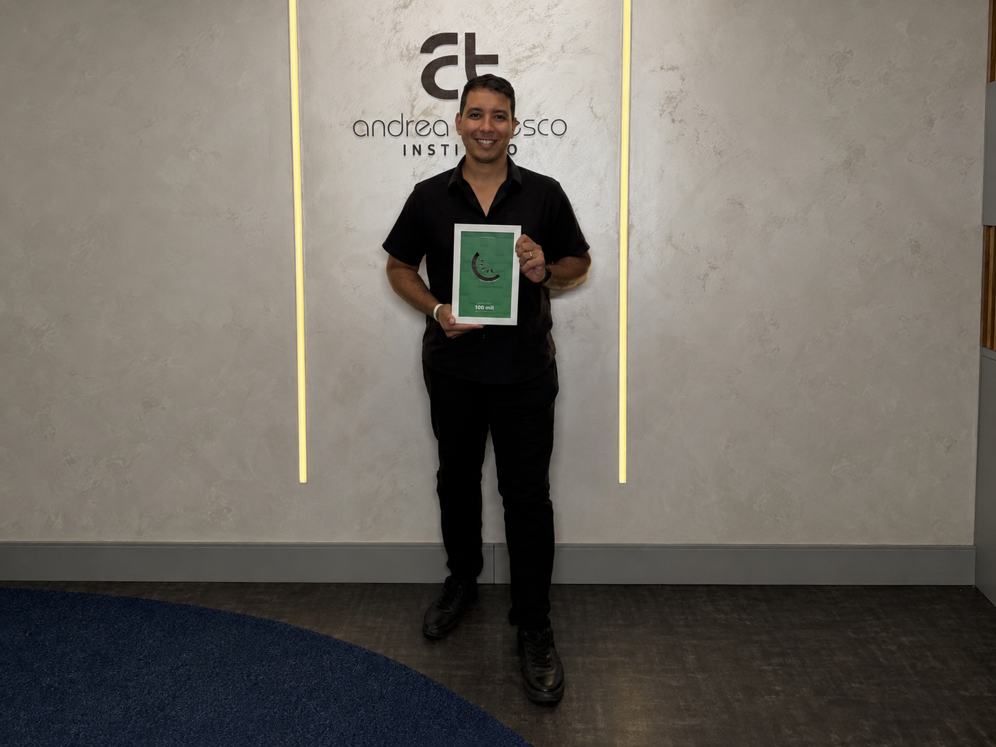 Nilton Junior recebendo uma placa de premiação da Kiwify no Instituto Andrea Tedesco